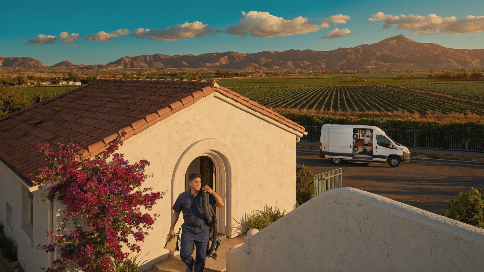 Technician carrying an extraction hose to a Spanish style home in Camarillo, California at golden hour